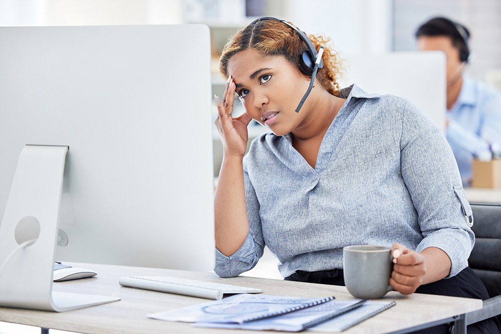 Tired, frustrated and stressed call center agent with a headache while working in customer service. Female IT support assistant struggling with a migraine and feeling confused or anxious.